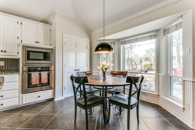 dining area featuring vaulted ceiling, dark tile patterned flooring, and ornamental molding