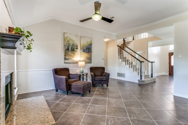 living area featuring stairway, visible vents, ornamental molding, a glass covered fireplace, and tile patterned floors