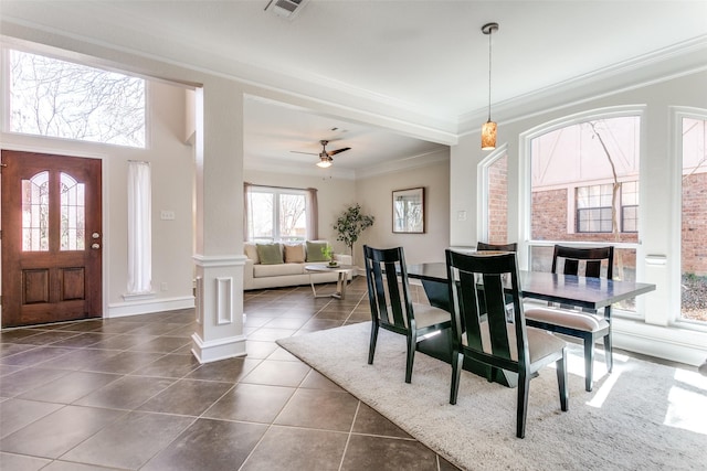 dining area with a ceiling fan, visible vents, decorative columns, crown molding, and dark tile patterned floors