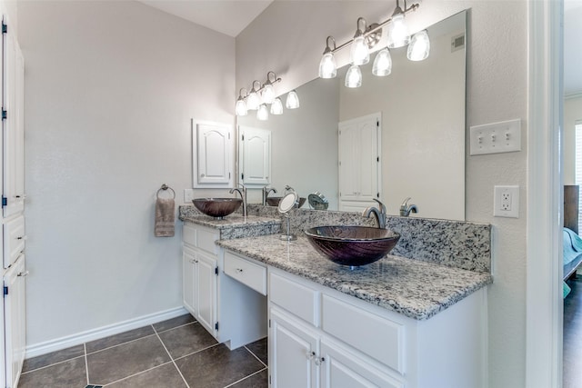 bathroom with tile patterned floors, double vanity, baseboards, and a sink