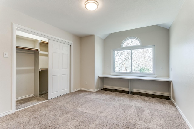 unfurnished bedroom with a closet, baseboards, carpet, and vaulted ceiling