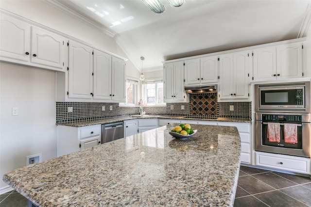 kitchen with dark tile patterned flooring, ornamental molding, range hood, appliances with stainless steel finishes, and white cabinets