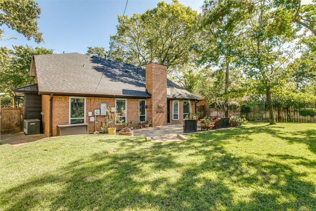 rear view of house with central air condition unit, a lawn, a patio, fence, and brick siding