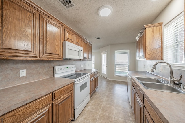 12104 Rolling Ridge Dr, Fort Worth, TX 76028 - kitchen with white appliances, a sink, a textured ceiling, brown cabinets, and light tile patterned flooring