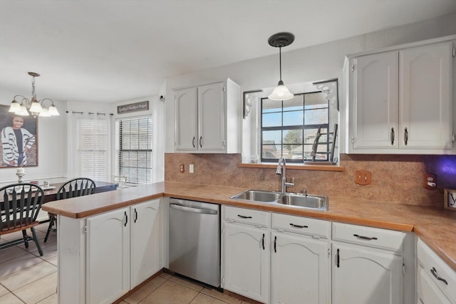 kitchen featuring a peninsula, a sink, light countertops, stainless steel dishwasher, and decorative light fixtures