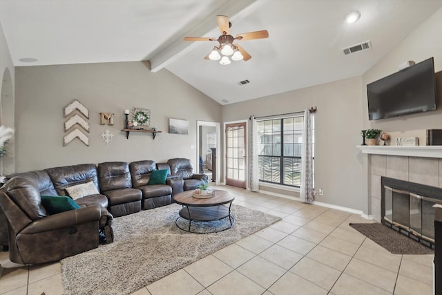 living area with lofted ceiling with beams, light tile patterned floors, a tile fireplace, and visible vents