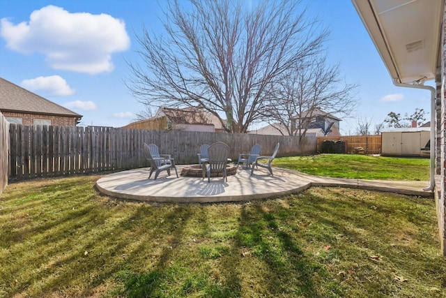 view of yard with a storage shed, an outdoor fire pit, a fenced backyard, an outbuilding, and a patio area