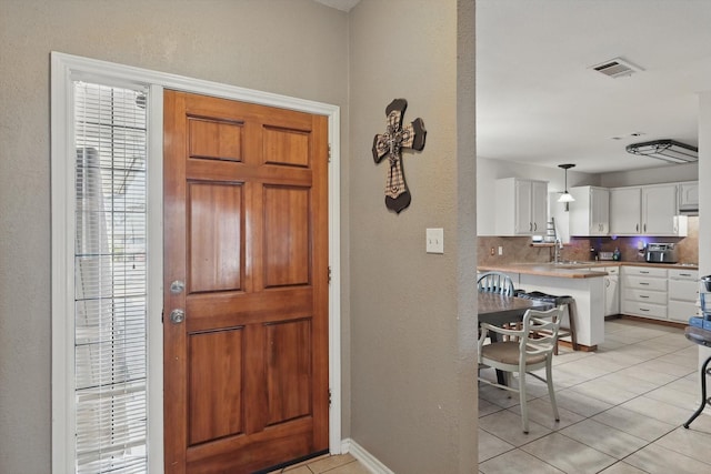 entrance foyer with a textured wall, light tile patterned flooring, visible vents, and baseboards