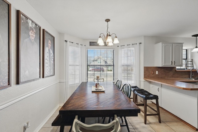 dining area with light tile patterned floors, baseboards, and an inviting chandelier