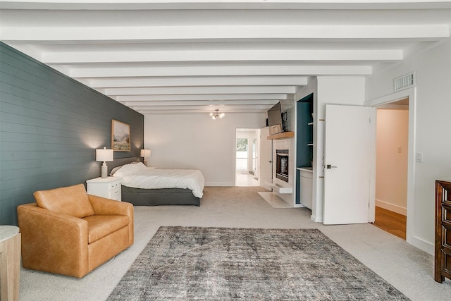 bedroom featuring light carpet, a fireplace with flush hearth, visible vents, baseboards, and beamed ceiling