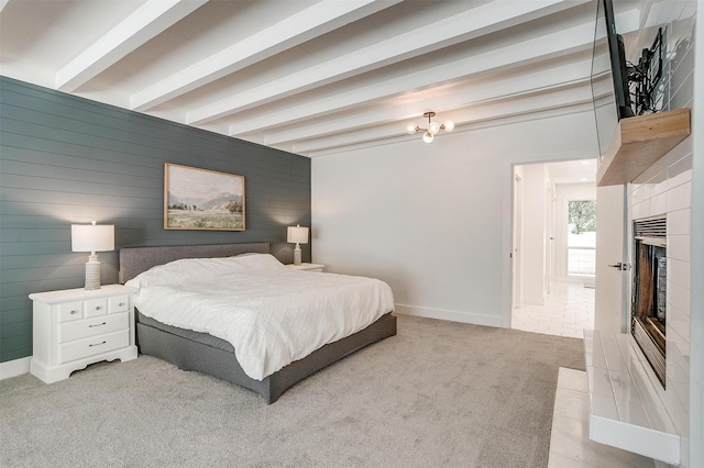 bedroom featuring light carpet, wooden walls, baseboards, a tile fireplace, and beamed ceiling