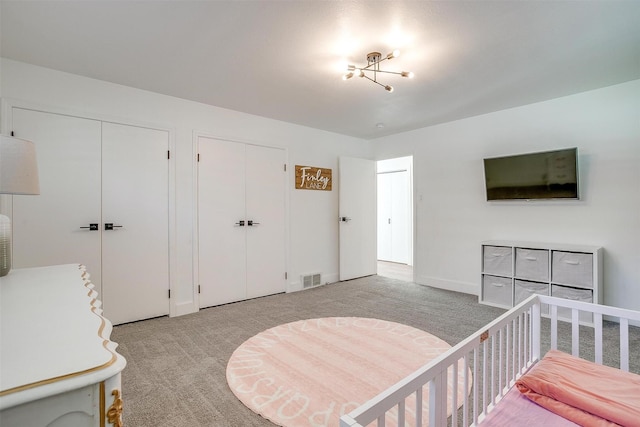 bedroom featuring visible vents, two closets, and light colored carpet