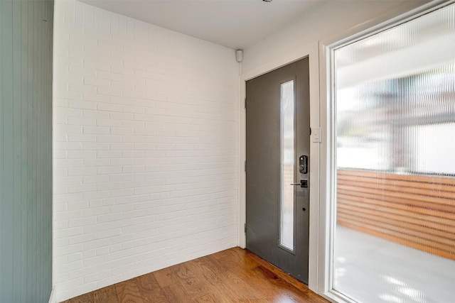 doorway to outside featuring brick wall and light wood finished floors