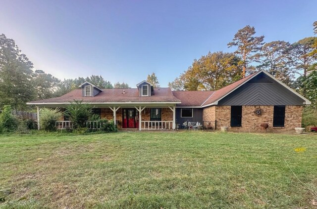 view of front of home with a front yard, covered porch, and brick siding