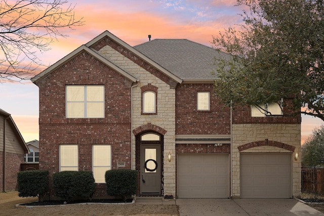 view of front of house featuring brick siding, a shingled roof, concrete driveway, stone siding, and an attached garage