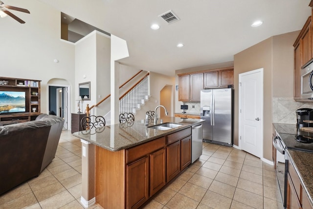 kitchen featuring visible vents, open floor plan, dark stone countertops, appliances with stainless steel finishes, and a sink