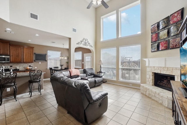 living room featuring light tile patterned flooring, visible vents, baseboards, and a ceiling fan