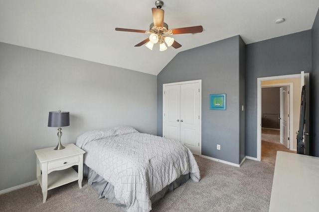 carpeted bedroom featuring vaulted ceiling, baseboards, a closet, and ceiling fan