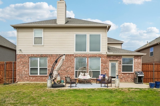 back of house featuring a yard, a patio area, brick siding, and a fenced backyard