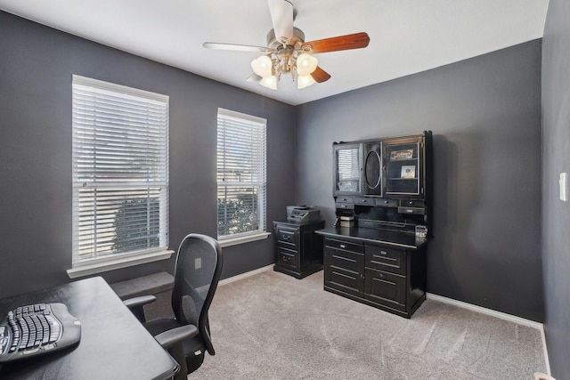 carpeted office space featuring baseboards and ceiling fan