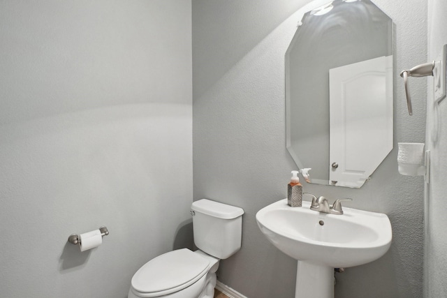 bathroom featuring toilet, baseboards, and a sink