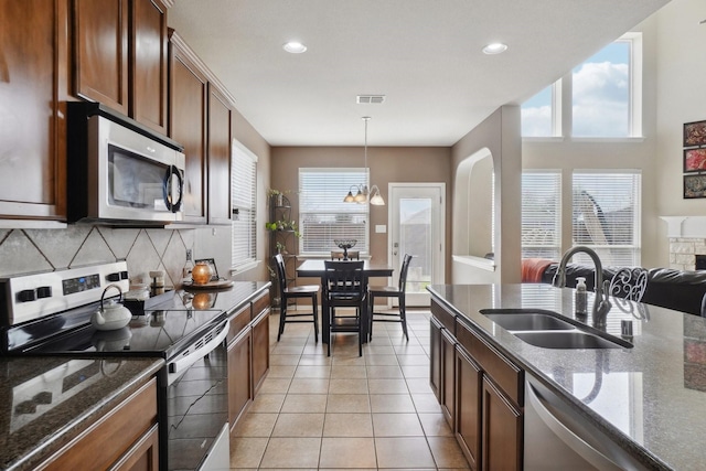 kitchen with a sink, tasteful backsplash, stainless steel appliances, light tile patterned flooring, and hanging light fixtures