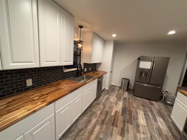 kitchen featuring tasteful backsplash, white cabinets, wood counters, appliances with stainless steel finishes, and a sink