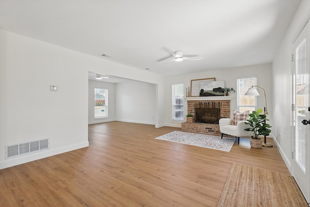 unfurnished living room with a fireplace, visible vents, baseboards, a ceiling fan, and light wood-type flooring