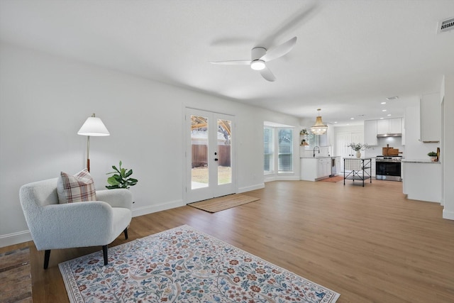 living room with ceiling fan, visible vents, baseboards, french doors, and light wood finished floors