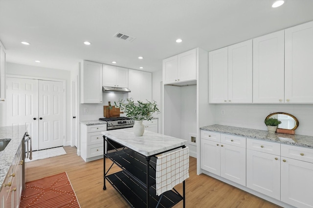 kitchen with visible vents, white cabinets, light wood-type flooring, under cabinet range hood, and recessed lighting