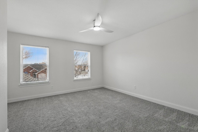 carpeted spare room with ceiling fan and baseboards