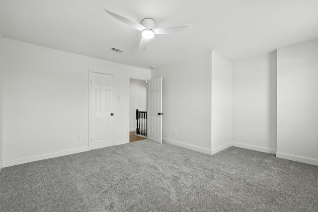 empty room with visible vents, carpet floors, a ceiling fan, and baseboards