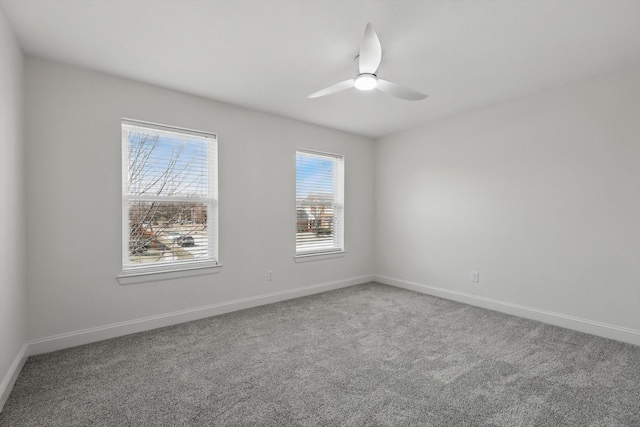 carpeted spare room with a ceiling fan and baseboards