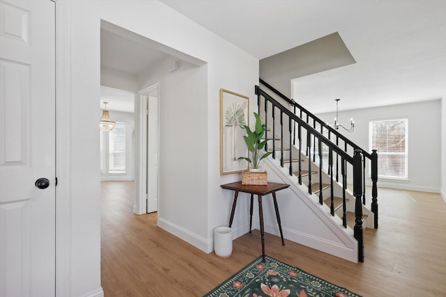 staircase with an inviting chandelier, baseboards, and wood finished floors