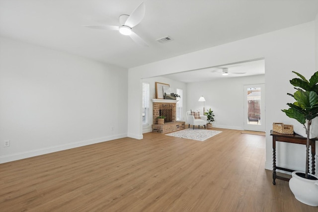 unfurnished living room with a fireplace, visible vents, a ceiling fan, light wood-style floors, and baseboards