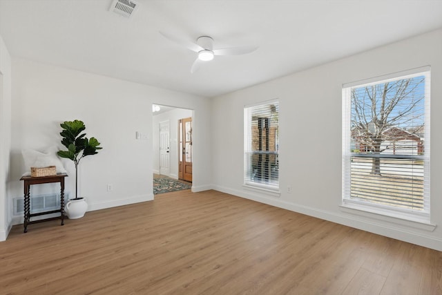 empty room featuring a healthy amount of sunlight, light wood-type flooring, visible vents, and ceiling fan