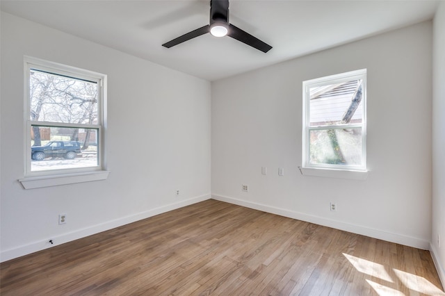 spare room featuring a ceiling fan, a wealth of natural light, baseboards, and wood finished floors