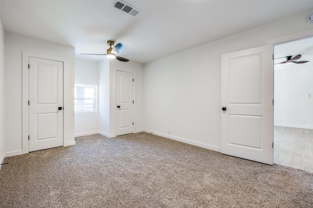 carpeted empty room featuring baseboards, visible vents, and a ceiling fan