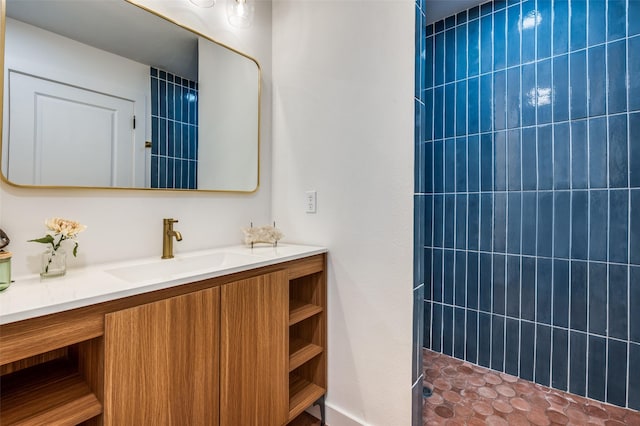 full bathroom featuring tiled shower and vanity