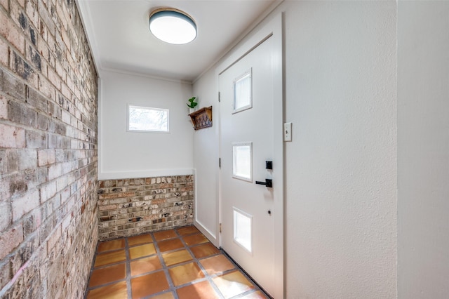 entryway with brick wall and crown molding