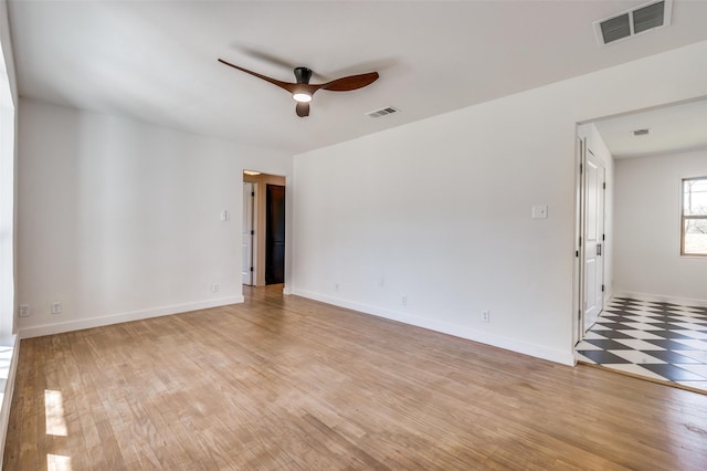 spare room with a ceiling fan, visible vents, light wood-style flooring, and baseboards