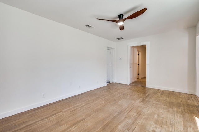 spare room featuring ceiling fan, light wood finished floors, visible vents, and baseboards