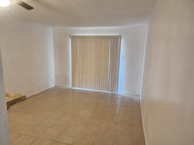 unfurnished room with ceiling fan, baseboards, and a textured ceiling