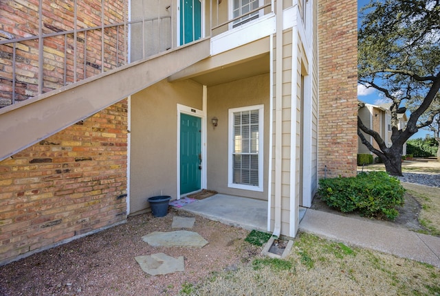 view of exterior entry with brick siding and stucco siding