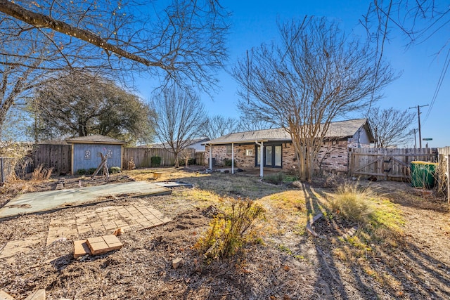 exterior space featuring a storage shed, a fenced backyard, an outdoor structure, a patio area, and brick siding