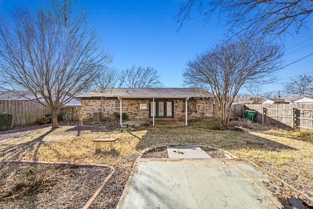 back of property with cooling unit, a fenced backyard, and brick siding