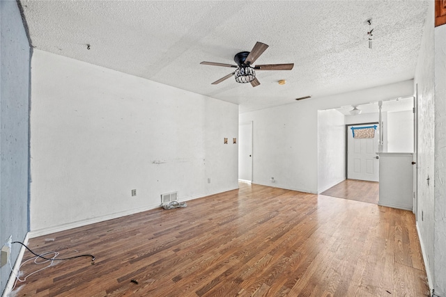 empty room featuring light wood-style floors, a textured ceiling, visible vents, and a ceiling fan