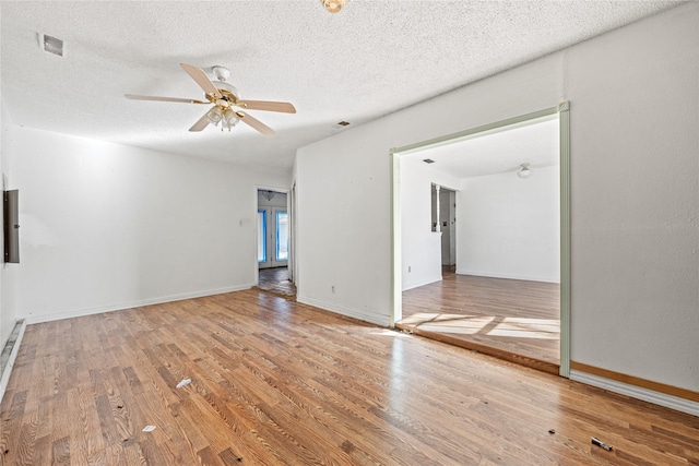 empty room with a textured ceiling, wood finished floors, and visible vents