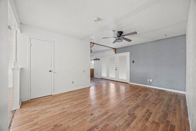 spare room with a textured ceiling, a ceiling fan, baseboards, french doors, and light wood finished floors