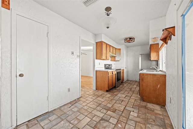 kitchen with visible vents, brown cabinets, light countertops, stainless steel range with electric cooktop, and under cabinet range hood